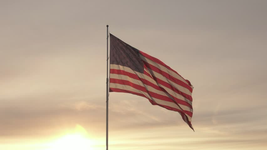 Steady shot of the American Flag under a clear sky on a windy day