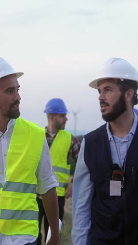 Team of worker specialists and engineers walking outdoors doing technical inspection of power station facility 