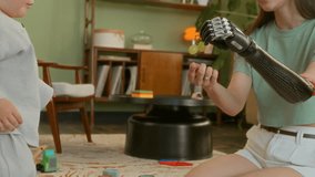 Young mother with prosthetic feeding her little son sitting on floor during playing toys in living room, she holds grapes in prosthetic hand and gives baby berries. Leisure together at home - Powered by Shutterstock - Get 15% off with code: PIKWIZARD15