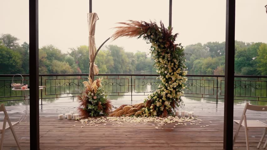 wedding arch of white rose flowers on the river bank before the wedding ceremony of the bride and groom, festive romantic decor