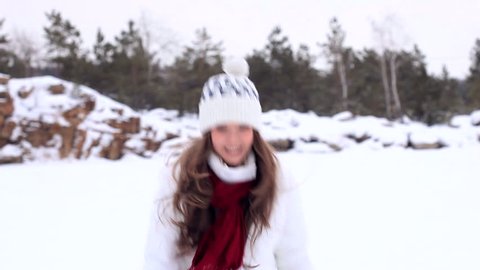 Beautiful girl in winter clothes throws a snowball into the camera!