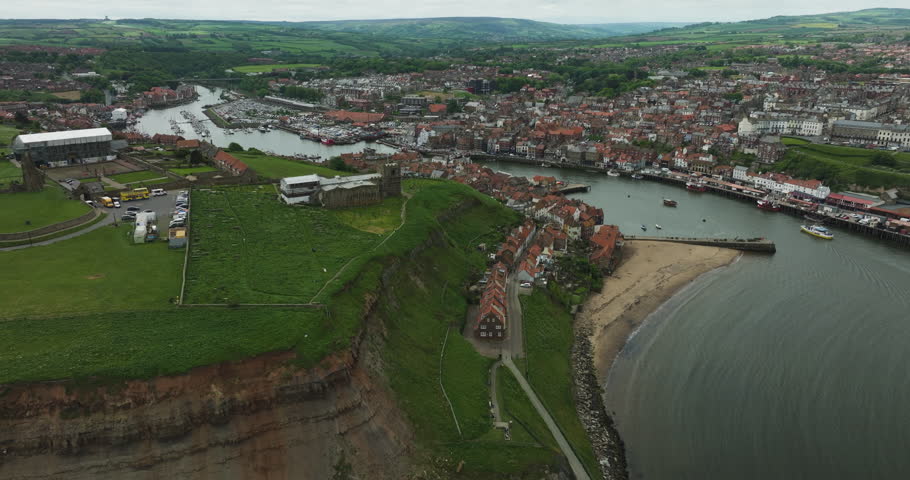 East Cliff Cottages And Pier At Whitby Seaside Town In Yorkshire, Northern England, United Kingdom. Aerial Drone Shot