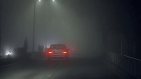 Car drive down a foggy road illuminated by street lights in city with headlights on. The scene is dark and mysterious, with the fog adding to the sense of horror - Powered by Shutterstock - Get 15% off with code: PIKWIZARD15
