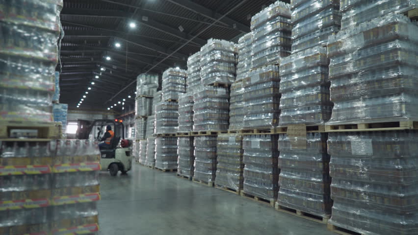 Using industrial pallet handler trucks to transport the wares in the storehouse. Truck drivers transporting the collected wares at the facility. Truck workers transporting the stocked wares.