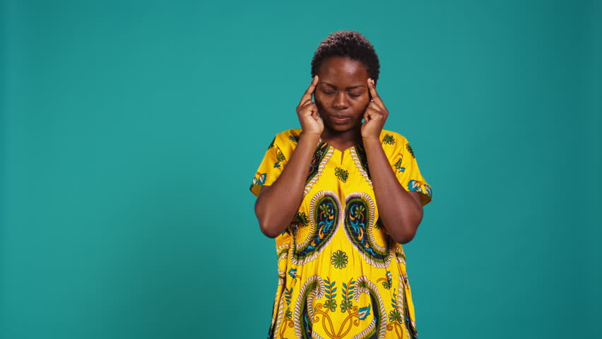 Sick unwell person rubbing temples because of a headache in studio, having flu symptoms and trying to cure a painful migraine. Woman feeling pressure and tension, stress. Camera B.