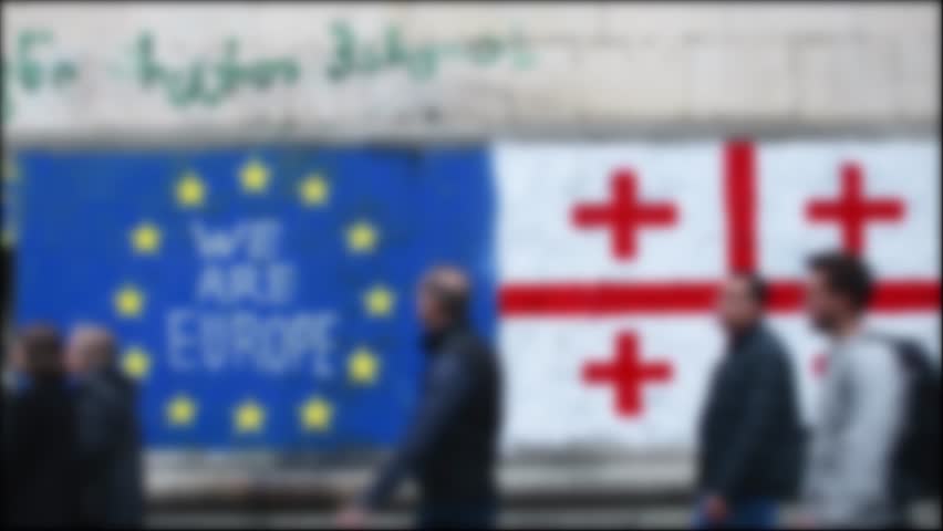 Blurry copy space banner background Georgian and EU Flag on wall with written statement "we need EU". Integration process to EU concept