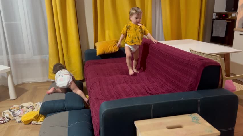 children playing on the sofa. happy family kid dream concept. children play getting on and off the sofa. little boy and girl playing on a blue sofa at home, close up lifestyle