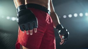 Close Up Portrait of a Combat Sports Athlete in Red Shorts with Focus on His Black Gloves. Athlete Standing Inside the Octagon, Preparing to Fight for the Belt. Determined Sportsman Ready for Battle - Powered by Shutterstock - Get 15% off with code: PIKWIZARD15