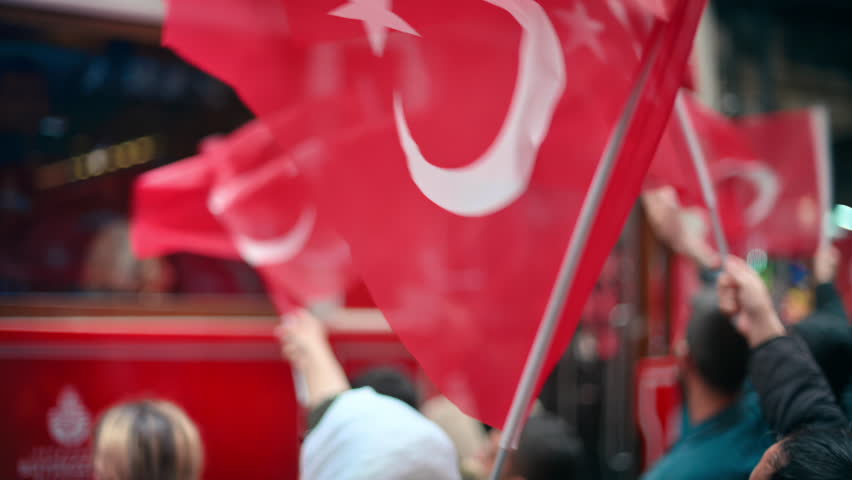 Multiple people waving turkish flags in city downtown at the Commemoration of Ataturk, Youth and Sports Day in Istanbul, Turkey. Slow motion
