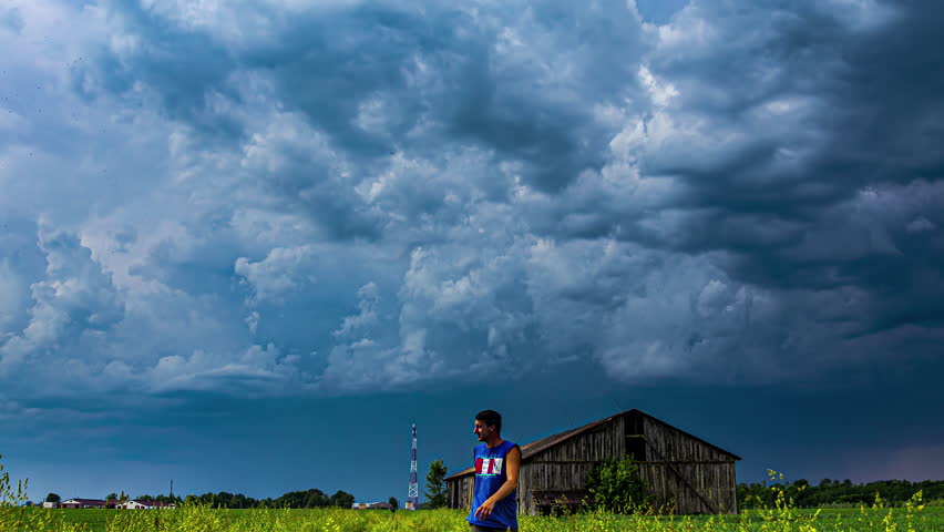 Storm clouds gather over an old barn in a rural field, showcasing nature