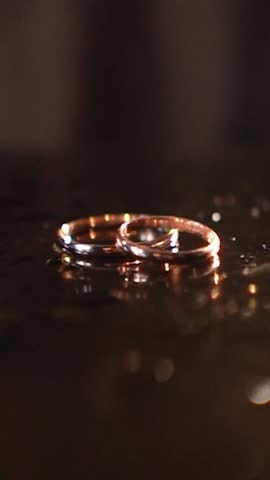 close-up of the wedding rings of the bride and groom before the outdoor ceremony lie on the table and are watered with drops of perfume and eau de parfum