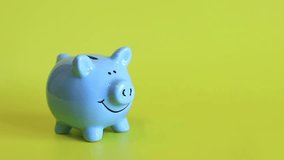 Piggy bank on a yellow background. Close-up of a cute blue piggy bank. Save money for your dream. A woman's hand puts coins into a piggy bank. Save, collect money - Powered by Shutterstock - Get 15% off with code: PIKWIZARD15