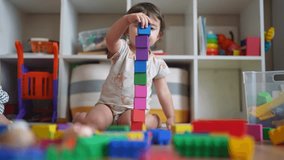 baby plays with toy blocks on floor. development of fine motor skills in children concept. baby daughter girl builds a lifestyle tower from toy cubes indoors kindergarten - Powered by Shutterstock - Get 15% off with code: PIKWIZARD15