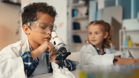 Young school boy and girl explore sample under microscope, conduct lab research - Powered by Shutterstock - Get 15% off with code: PIKWIZARD15