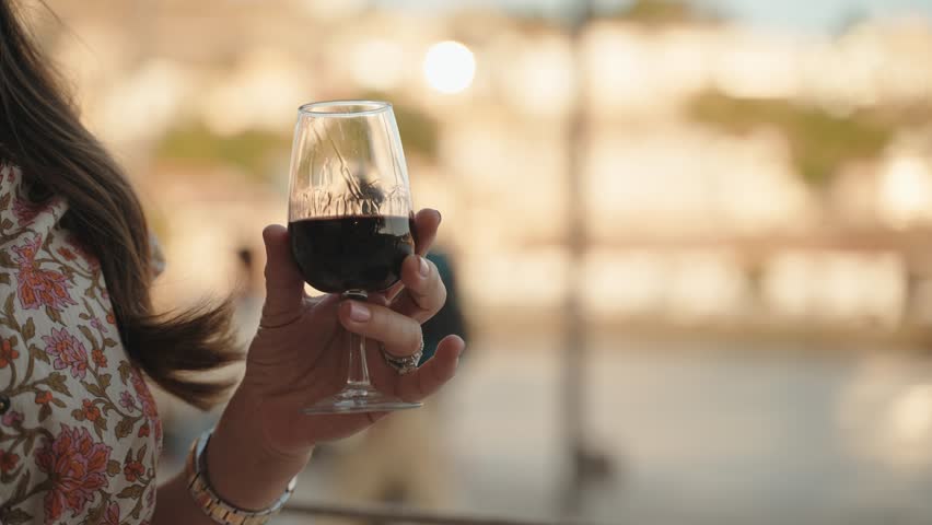 Woman elegantly holding a glass of Port wine at a cafe in Porto, Portugal