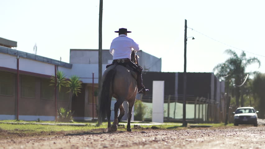 A gaucho in traditional attire riding through the streets of a small town in Corrientes, Argentina, near the border with Brazil.