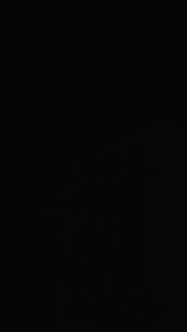 Vertical video. A woman in a blanket opens the dark curtains and steps out into the sunny balcony overlooking the sea.