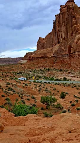 A vertical shot of vehicles on the road and the rock formations at Arches National Park in south Utah on a sunny day