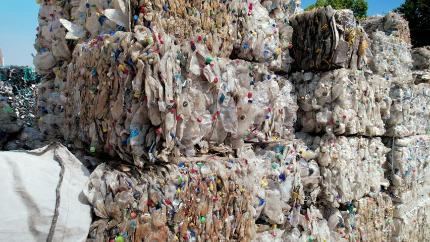 Multiple cubes of compressed plastic garbage at waste recycling factory in open air