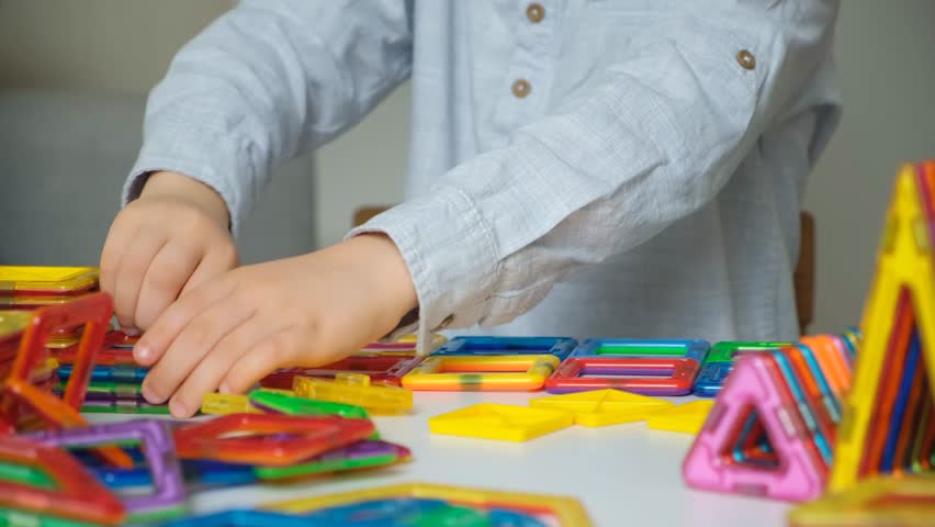 Child playing with magnetic constructor, hands close-up.