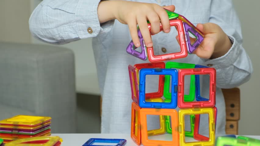 Child playing with magnetic constructor, hands close-up.
