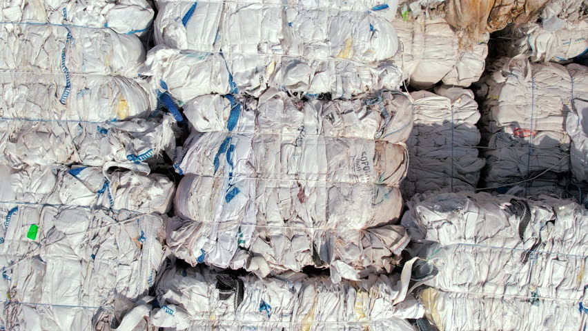 Multiple cubes of compressed fabric garbage at waste recycling factory in open air