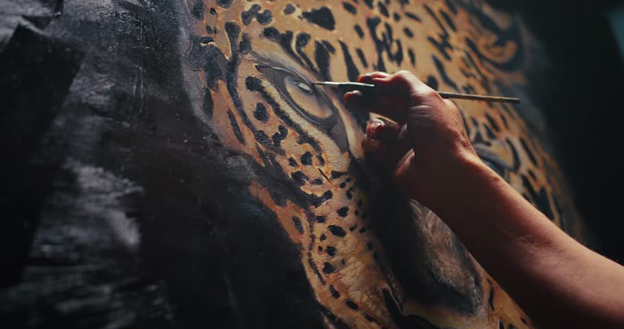 A skilled artist meticulously paints a lifelike leopard on a canvas in a studio setting, using a palette of various paints.