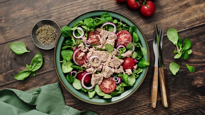 Canned tuna salad with tomatoes lambs lettuce corn salad and onions, top view, stock video 4k