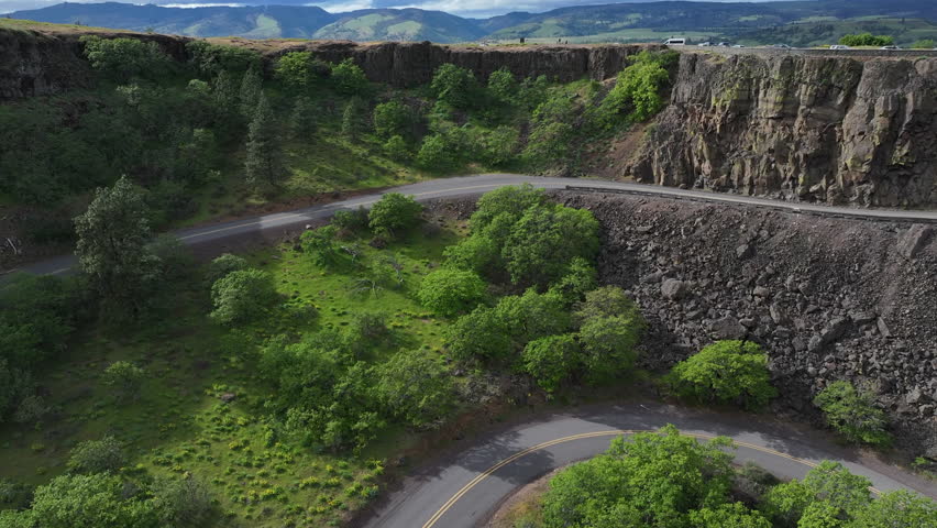 An aerial drone shot captures the scenic roadway winding through Oregon