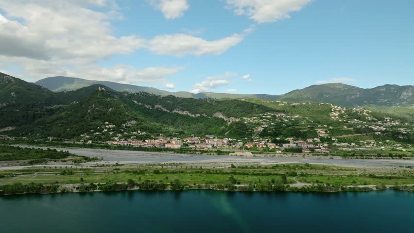 An aerial footage of Broc Lake with Var River and Les Condamines neighborhood in the background on a sunny day in Saint-Martin-du-Var, France