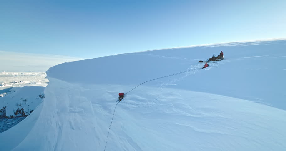 Group of people relax Antarctica glacier aerial view. Snow-covered slope, blue sky in sunny day. Discover South Pole beauty. Antarctica travel, expedition, exploration. Man digging snow with shovel