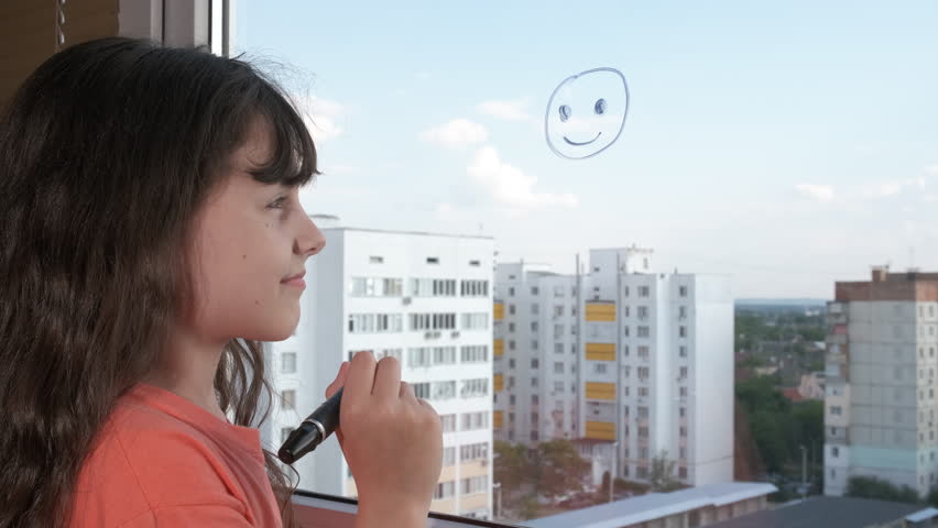 Drawing child on window with felt pen. A view of drawing little girl with felt pen on window during day time.