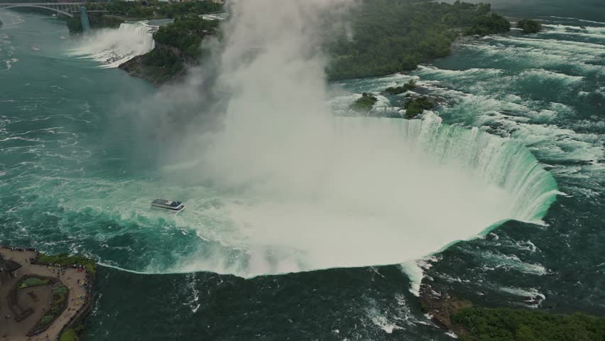 Cinematic shot of a drone on Canadian side view of Niagara Falls, Horseshoe Falls and boat tour at sunset in Niagara Falls, Ontario, Canada Aerial view