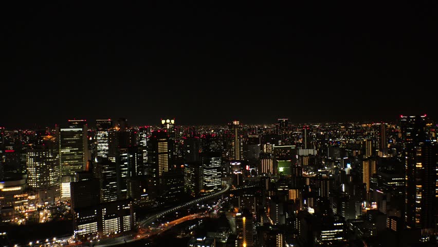 OSAKA, JAPAN - JUL 2019 : Aerial high angle view of CITYSCAPE of OSAKA at night. View of buildings and street around Osaka and Umeda station. Japanese urban city nightlife and business concept video.
