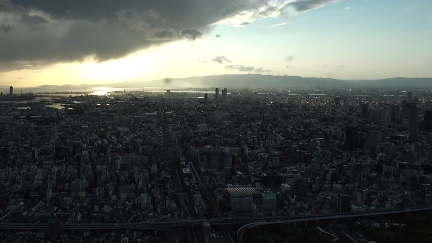 OSAKA, JAPAN : Aerial high angle sunset view of CITYSCAPE of OSAKA. View of buildings and street traffic around Osaka bay and Kobe port. Long time lapse wide view shot, dusk to night.