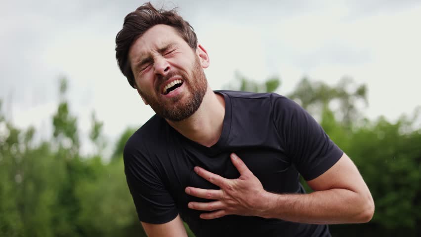Overwhelmed man running fast through local stadium and finishing workout for taking breath and regaining strength. Nervous jogging amateur suffering from strain in chest area and bending down. - Powered by Shutterstock - Get 15% off with code: PIKWIZARD15