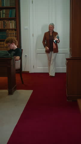 Vertical shot of a female lecturer walking through the classroom and supervising students during exams