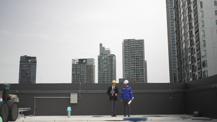 Maintenance engineers are checking cooling system at rooftop building. Blue collar worker and engineer.