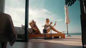 Young beautiful blonde girl reading a book while laying on a sunbed in a luxurious designer sea-view villa - Powered by Shutterstock - Get 15% off with code: PIKWIZARD15