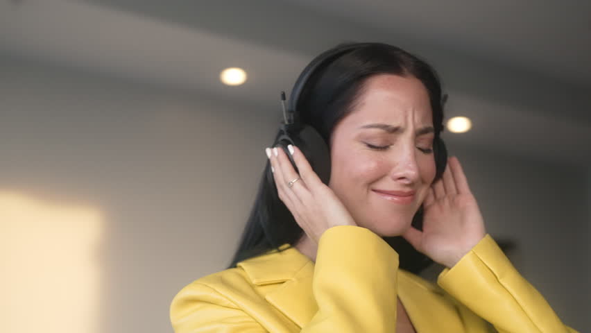 Excited young woman dancing with headphones on and listening to the music after work