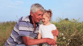 Happy grandfather with gray hair playing with his playful carefree granddaughter in the open countryside on a bright warm summer day looking and smelling daisies - Powered by Shutterstock - Get 15% off with code: PIKWIZARD15