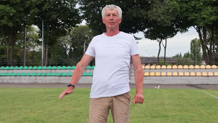 Aged runner enjoying outdoor exercises warming up body before jogging keeps his body in top physical condition during retirement having training at the stadium