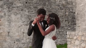 Beautiful loving African American couple romantically dancing near stone building or castle. Beautiful bride in white dress twirling in dance with her beloved man. Creating family. Wedding day concept - Powered by Shutterstock - Get 15% off with code: PIKWIZARD15