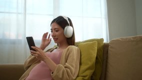 Happy pregnant woman listening to music with headphone and caressing her belly while sitting on sofa at home, concept of happy motherhood relaxing and waiting her childbirth.
 - Powered by Shutterstock - Get 15% off with code: PIKWIZARD15