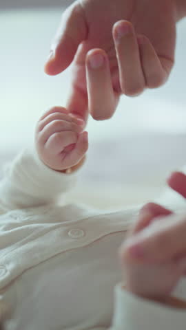 B roll Close-up little hand of child baby holding hand of mother, A newborn holds on to mom's, dad's finger, Love and relationship with infant, Care and support, Dreaming and protection