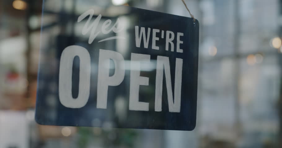 Close-up of Yes we are open sign on transparent glass shop door inviting customers in morning. Successful business and shopping concept.