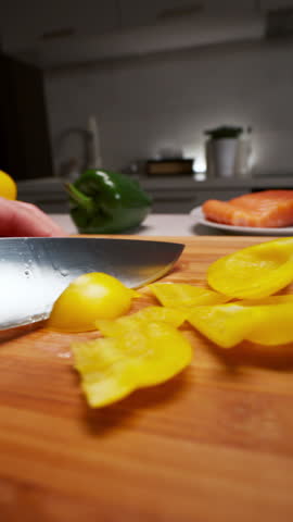 A person skillfully prepares a variety of fresh ingredients on a cutting board, including cutting yellow peppers and lemons. The video showcases the process of food preparation and cooking