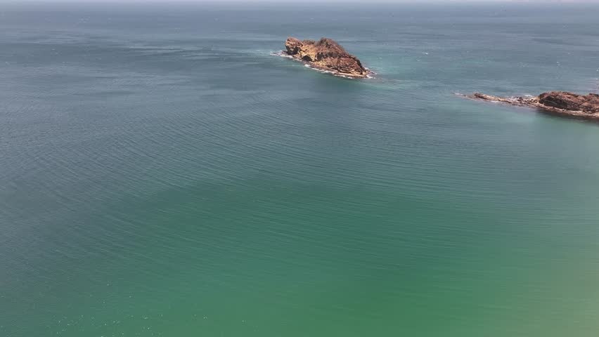 A drone view over the Pacific Ocean showcasing El Jobo beach with cliffs in Guanacaste, Costa Rica on a sunny day