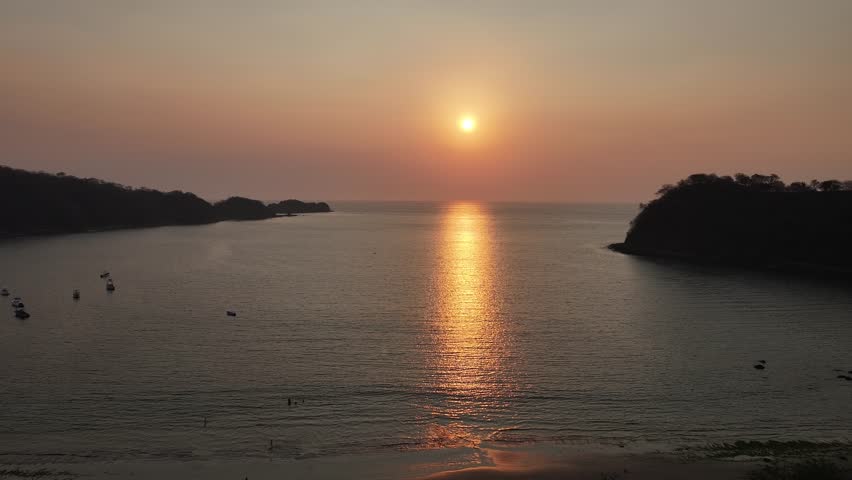 An aerial scenery of epic sunset with pink sky over the Pacific Ocean with some moored boats in El Jobo, Costa Rica