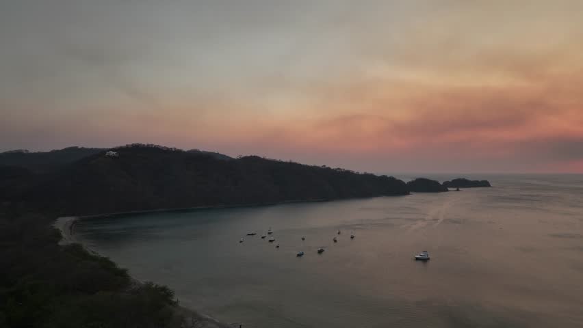 An aerial scenery of epic sunset with pink sky over the Pacific Ocean with some moored boats in El Jobo, Costa Rica